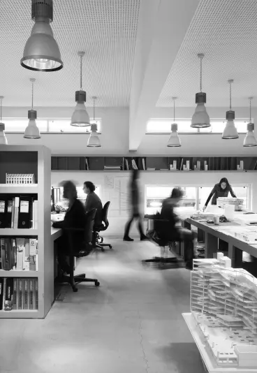 Minimalist black and white workspace with a MacBook laptop, desk, and indoor plants in natural sunlight